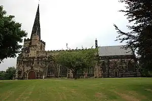 A colour photograph of a stone-built English-style church with a spire