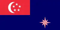 A red rectangle at the top left corner of the flag, charged with a white crescent and five white stars arranged in a pentagon. The rest of the flag is coloured blue. At the bottom right part of the flag is an eight pointed star that is alternating red and white.